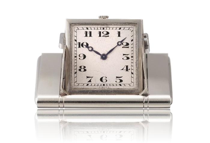 1928 - Montre de poche "surprise". Or gris 18K, cadran argenté, chiffres arabes noirs. Ouverture des volets par pression sur les flancs de la boîte.